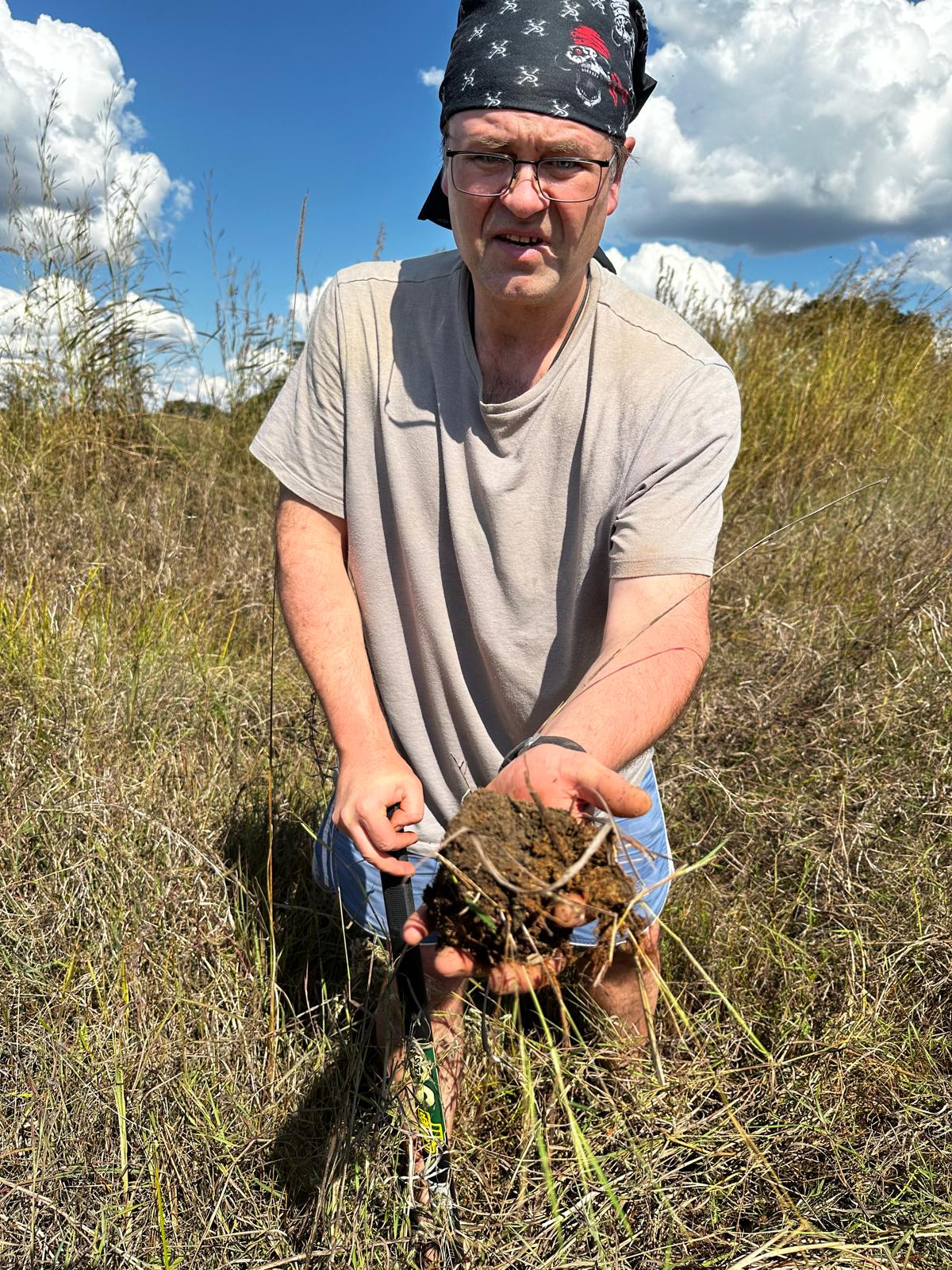 Matej holding dirt in a field
